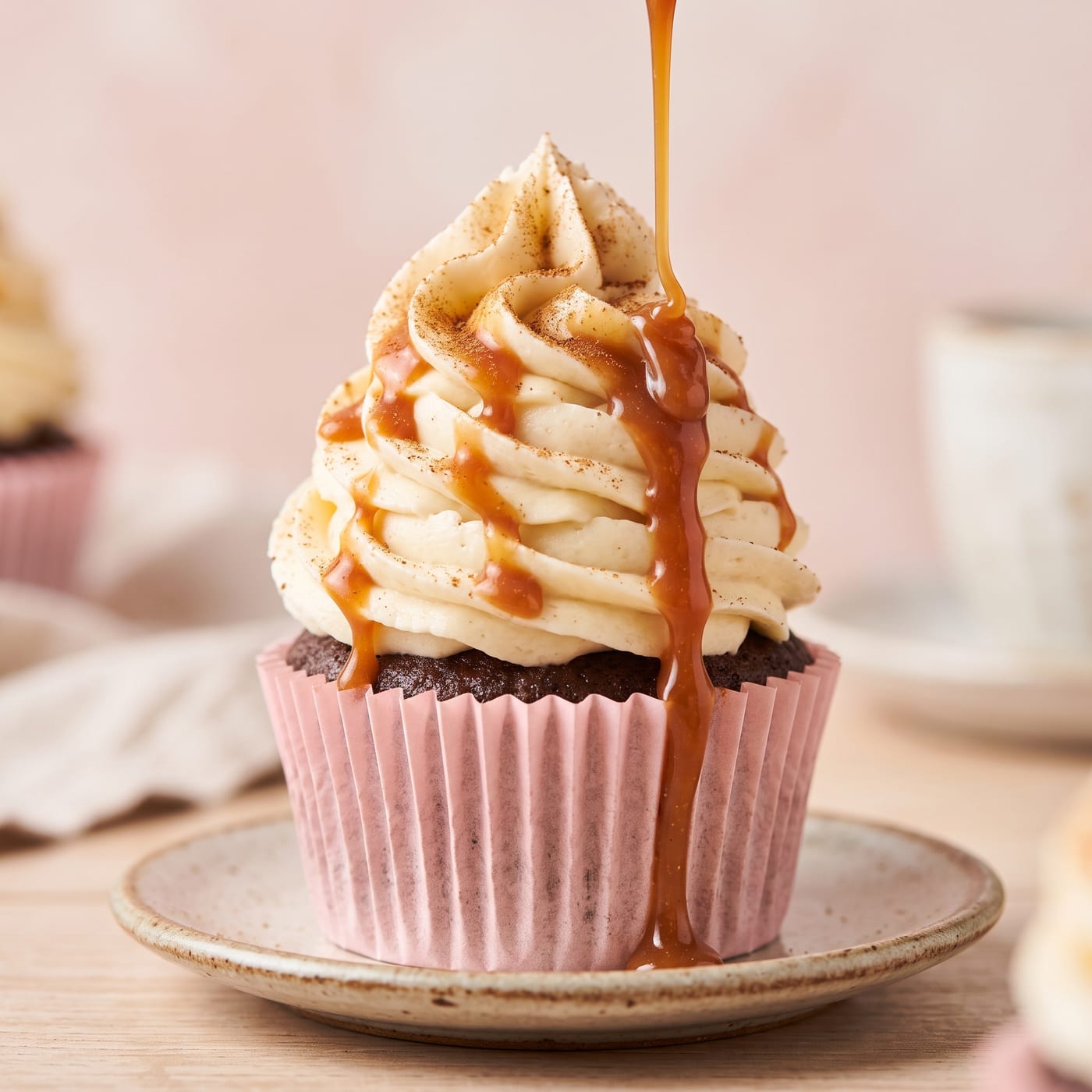 Close up of caramel drizzle dripping down swirled frosting on an apple cider cupcake