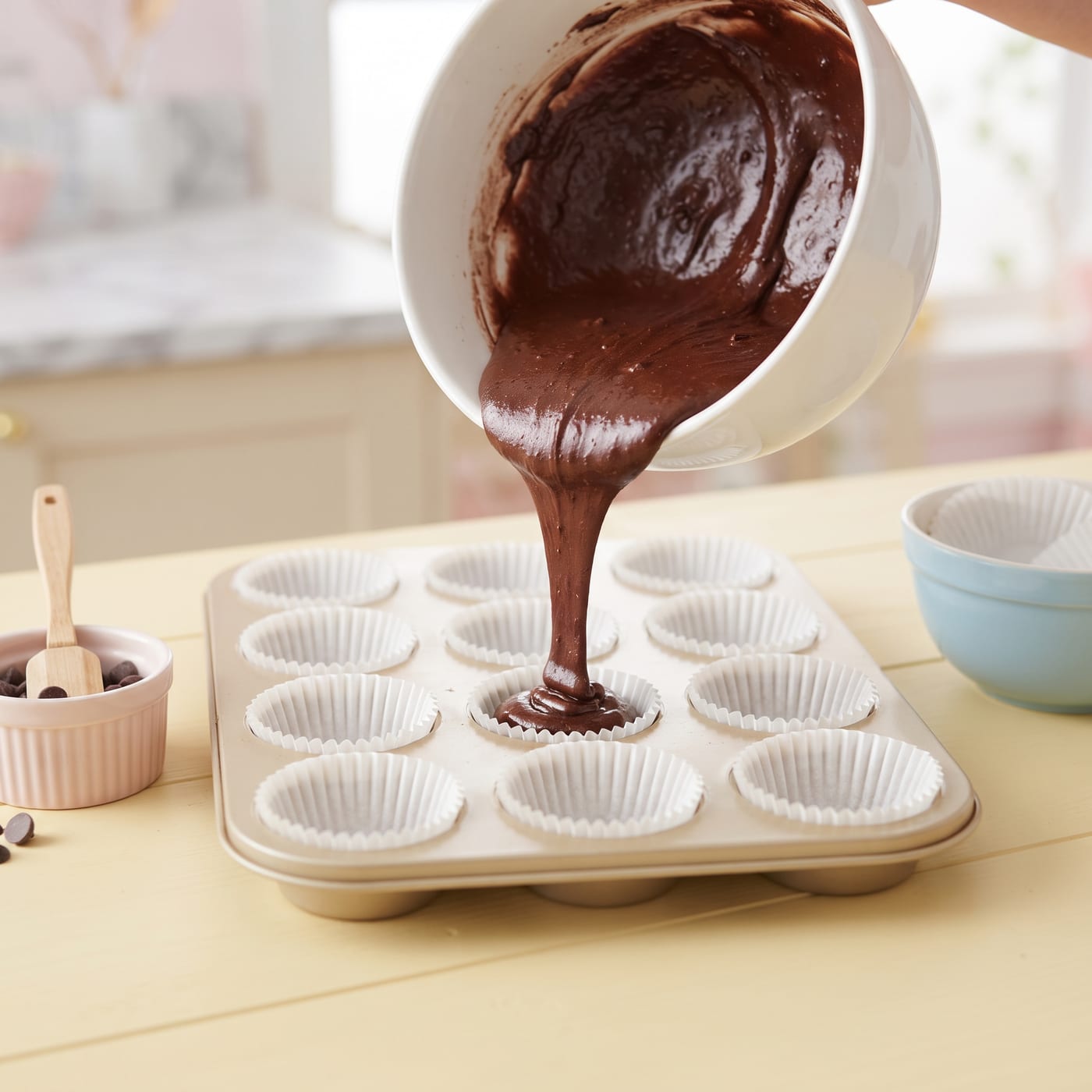 Chocolate cupcake batter being poured into lined muffin pan