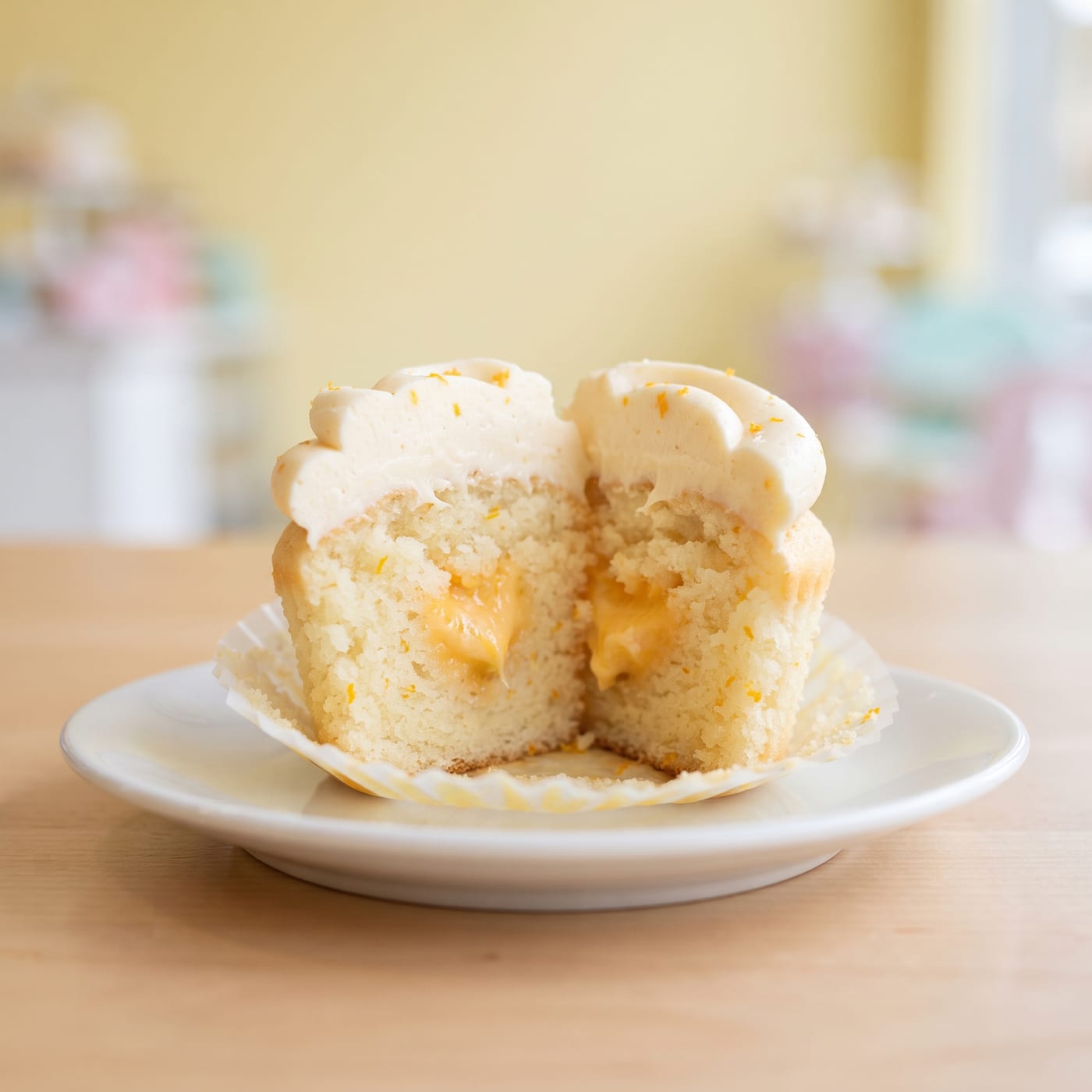 Close up cross section of an orange vanilla cupcake showing soft crumb and citrus specks