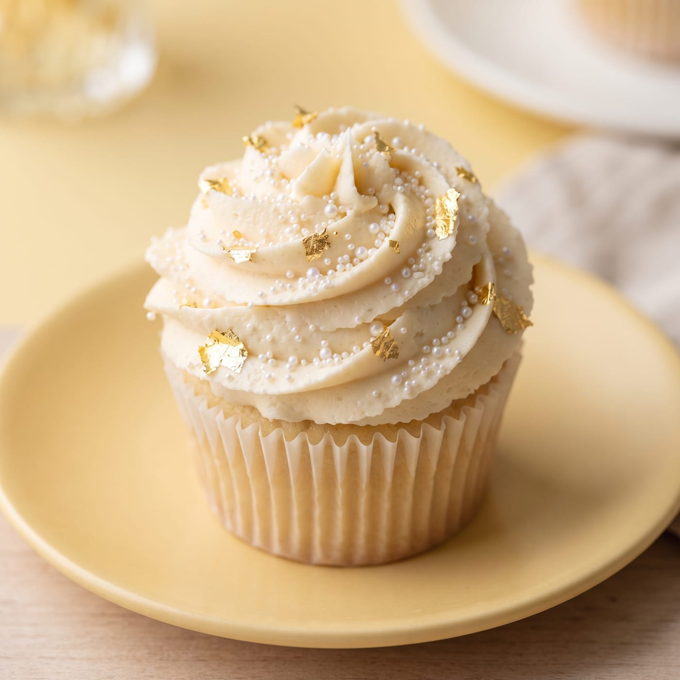 Close up of micro pearls and gold leaf detail on a pastel frosted cupcake