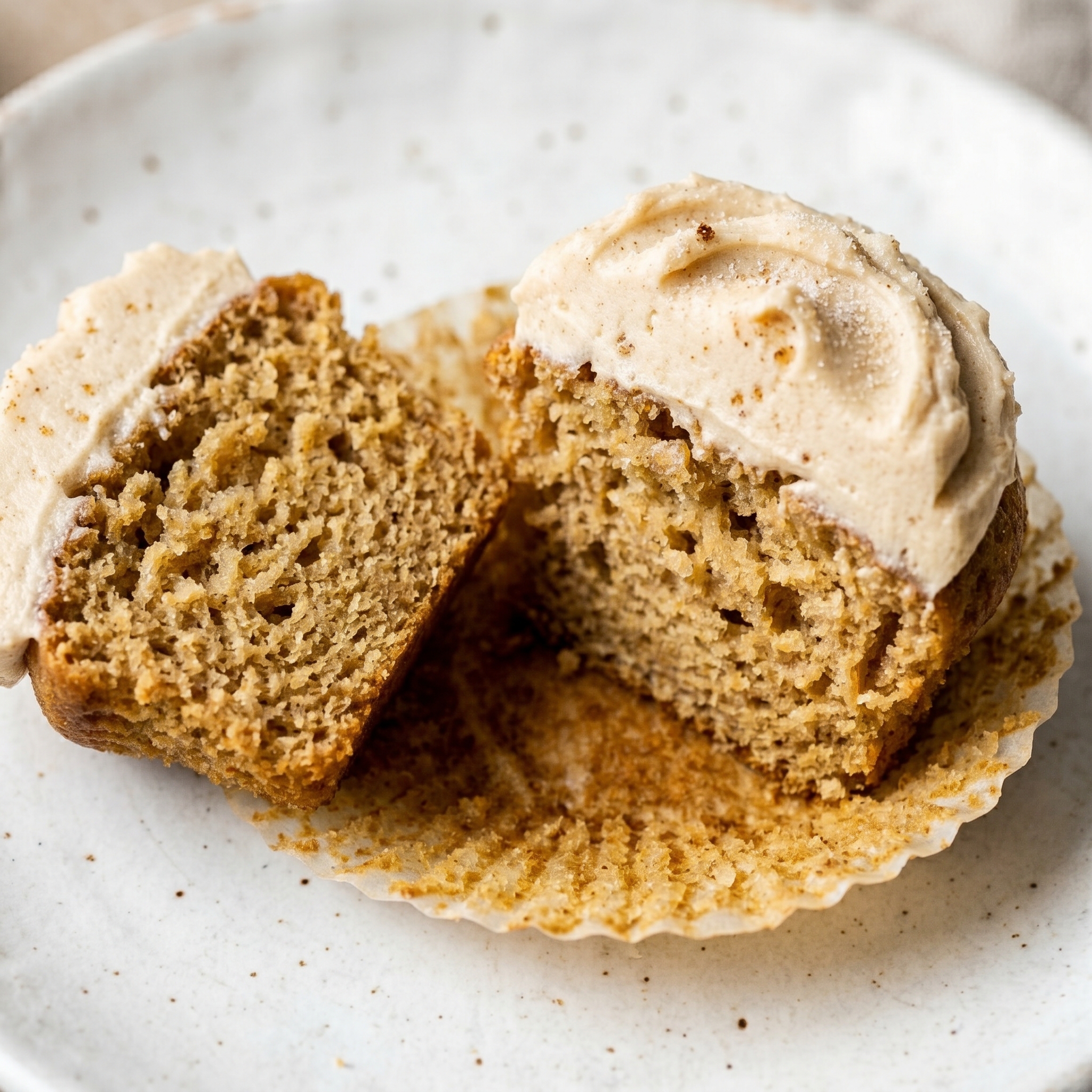 Cross-section of a brown butter cupcake showing golden crumb and pale tan frosting