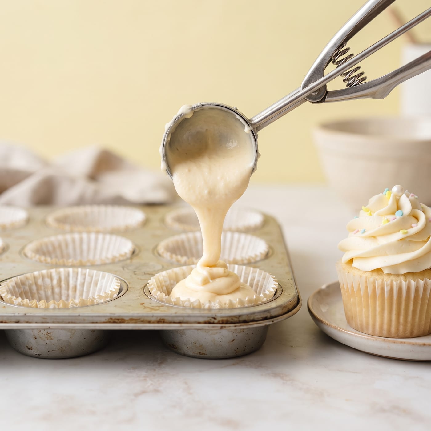 Ice cream scoop releasing a level portion of batter into a cupcake liner