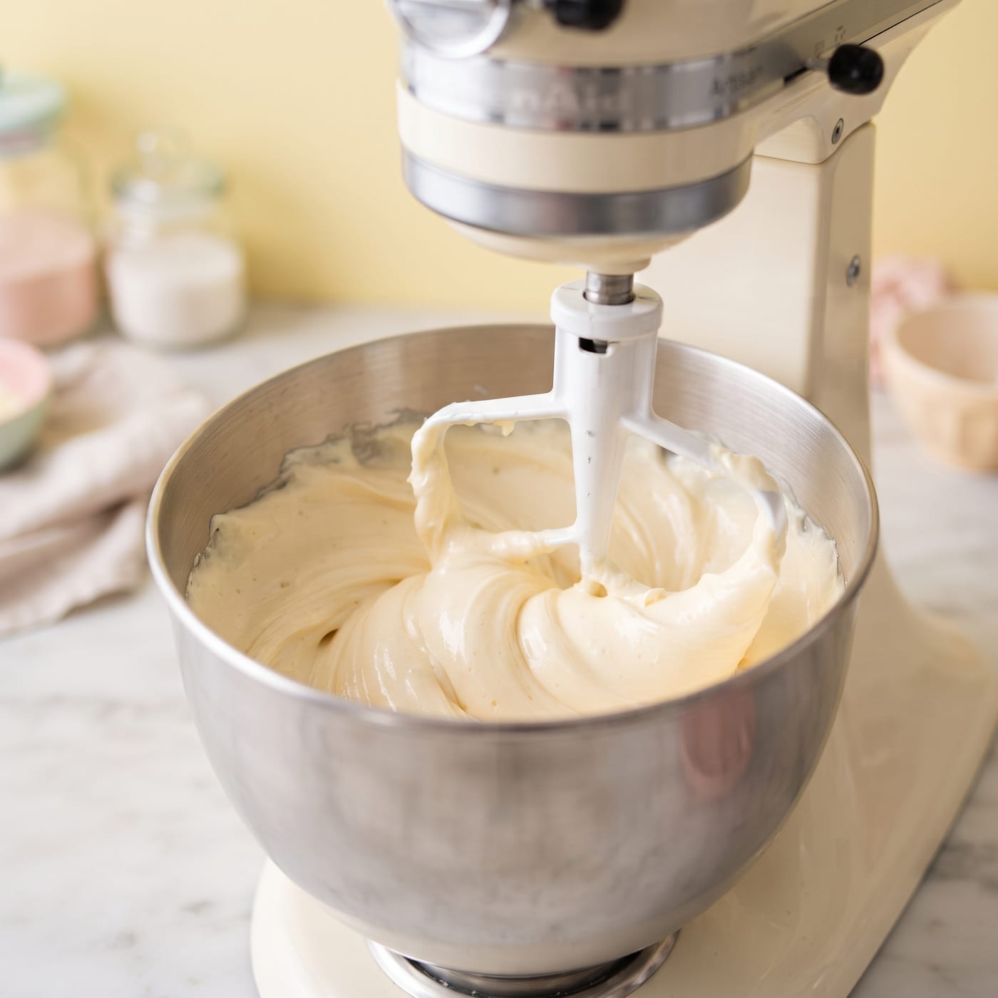 Stand mixer bowl showing frosting being beaten smooth on low speed to remove air bubbles