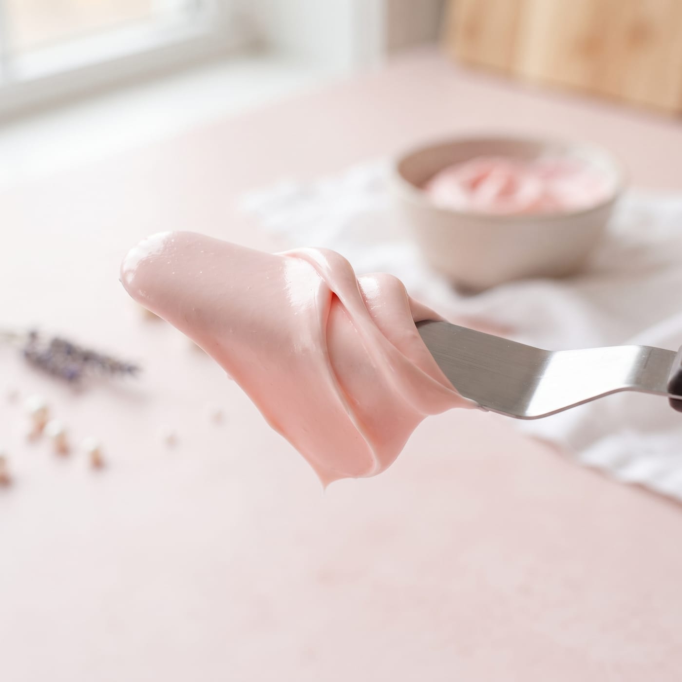 Close up of silky lump free frosting texture on a spatula showing a smooth glossy finish