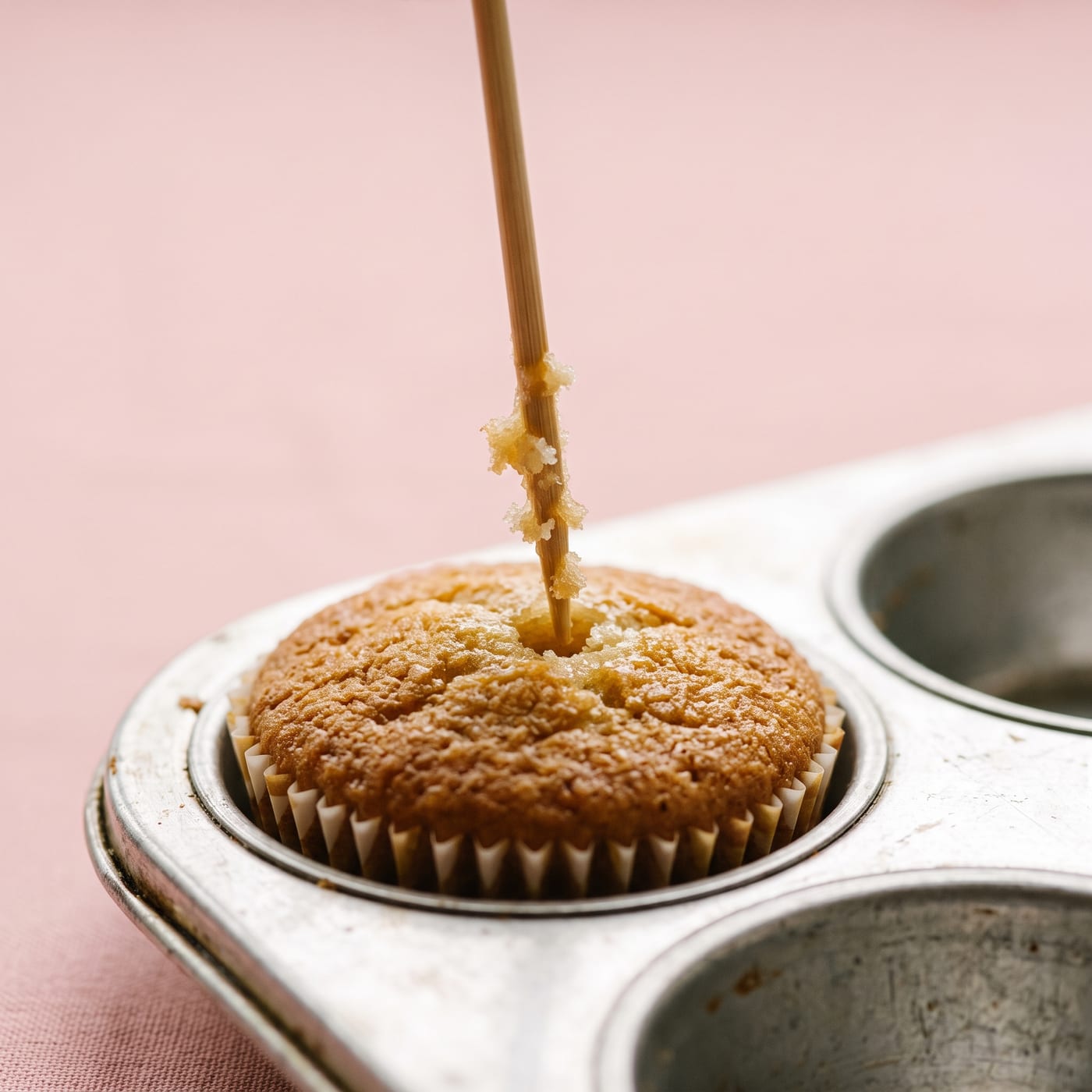 Close up of a toothpick being pulled from a cupcake showing a few moist crumbs