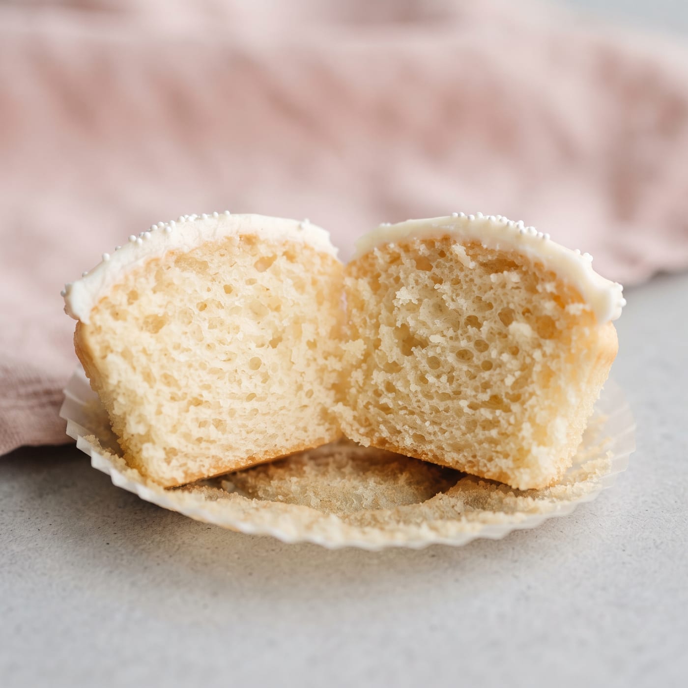 Close up of a cupcake crumb showing even small air pockets against a blush pink background