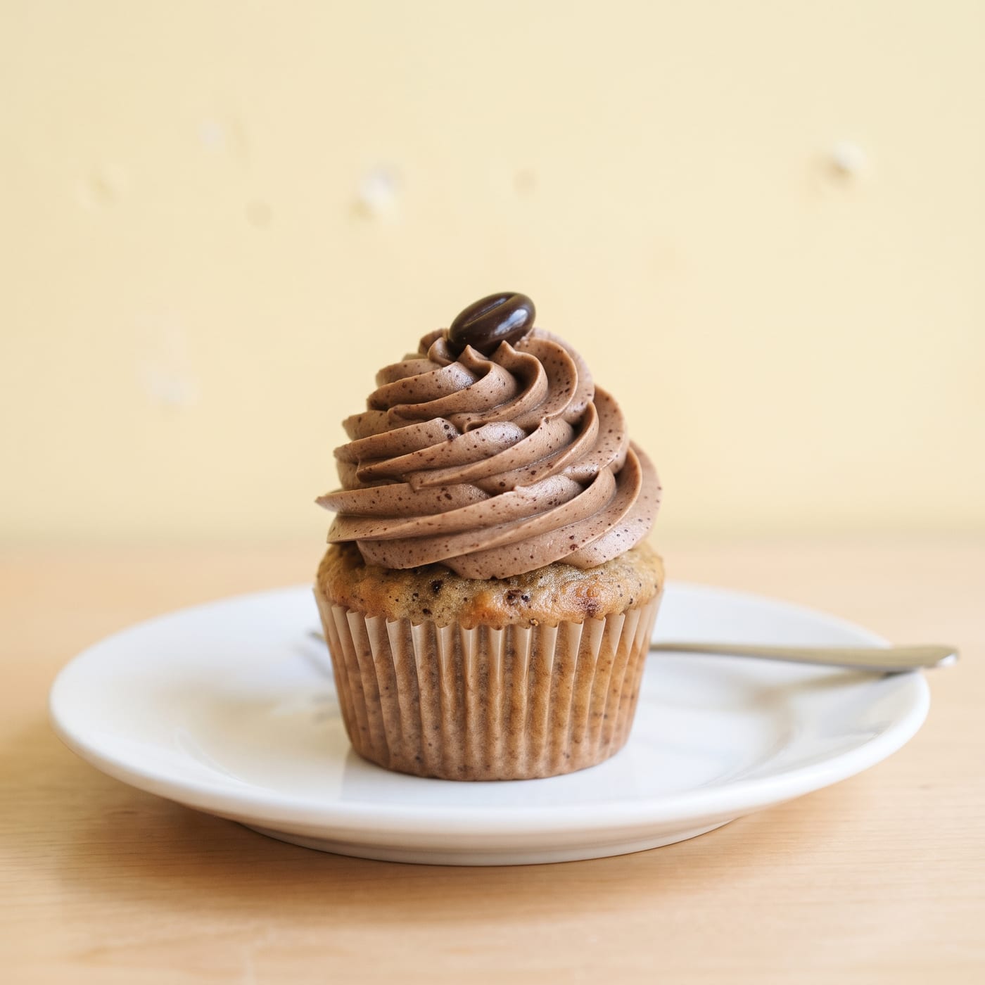 Close up of mocha cream swirl frosting with coffee bean garnish on a keto cupcake