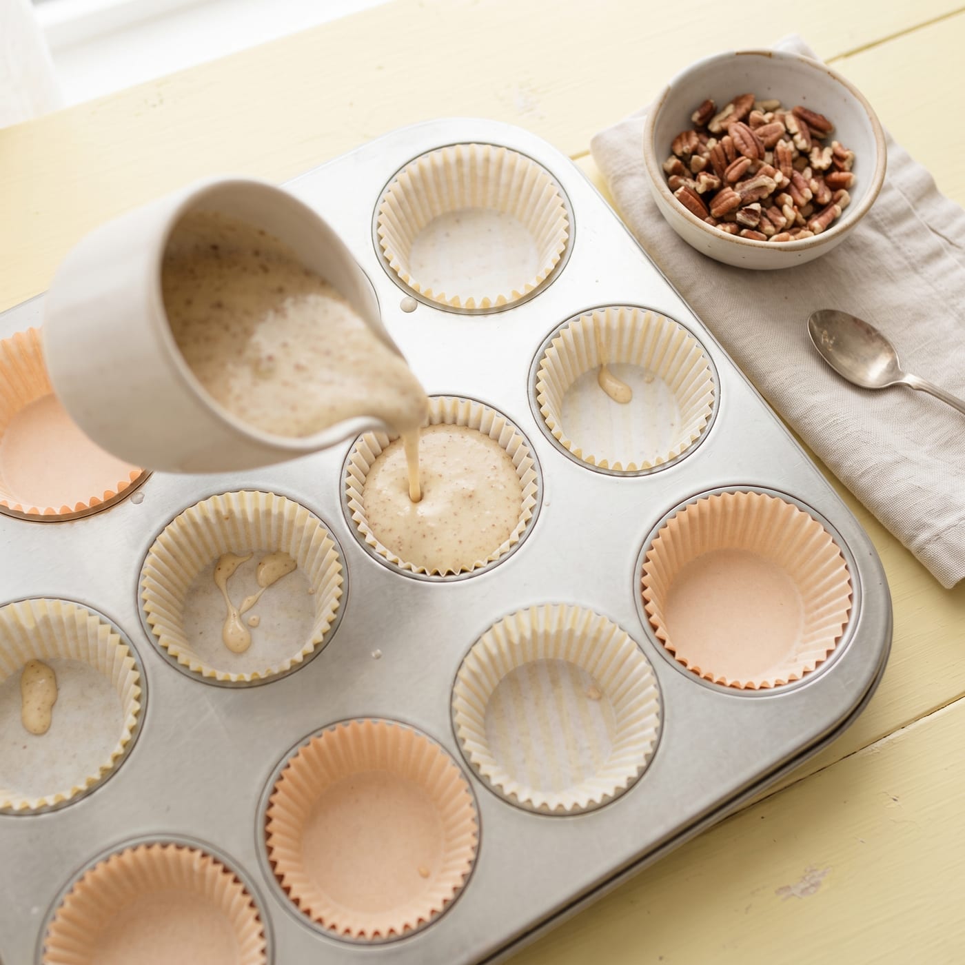 Almond flour cupcake batter being poured into a lined muffin pan