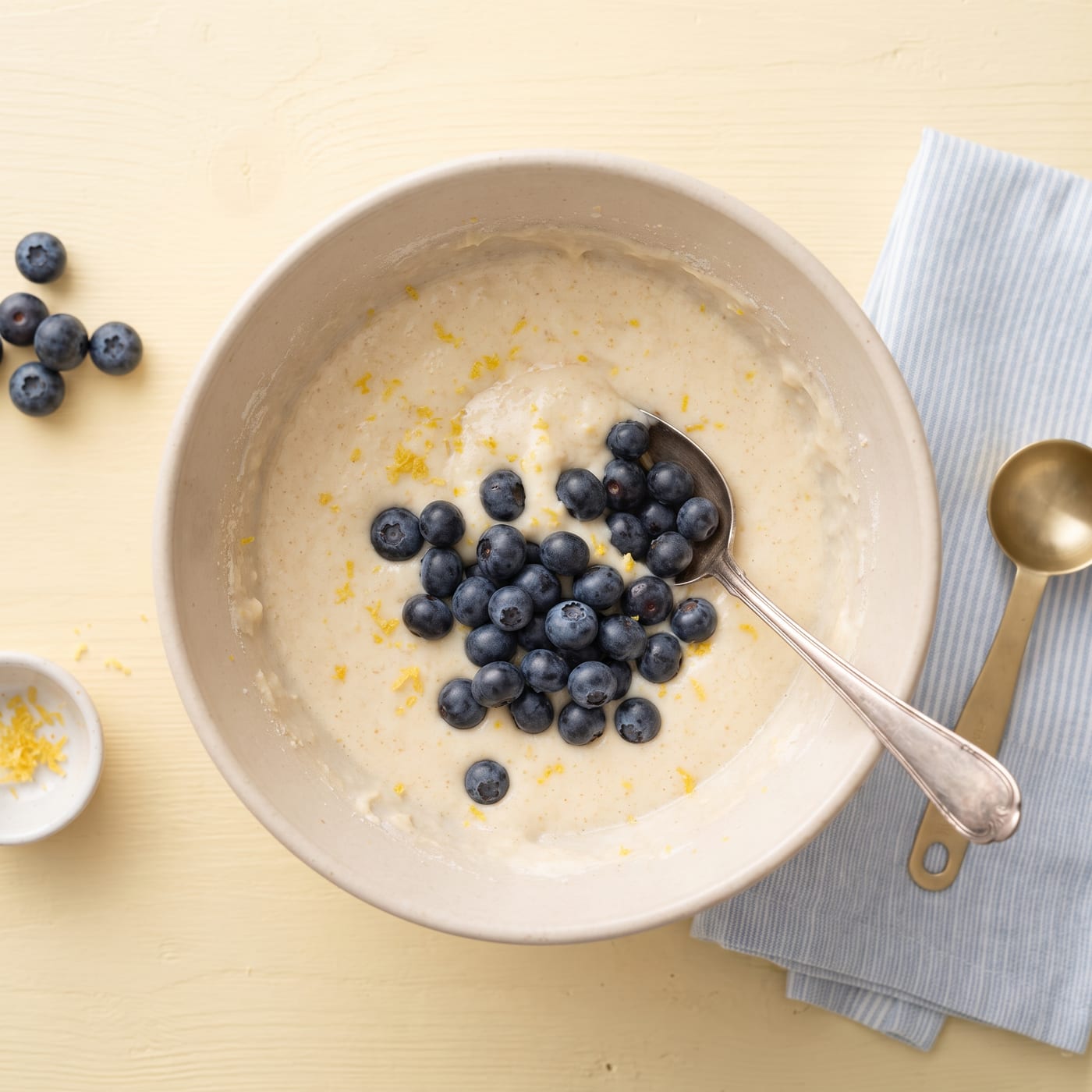 Bowl of almond flour cupcake batter with fresh blueberries being folded in