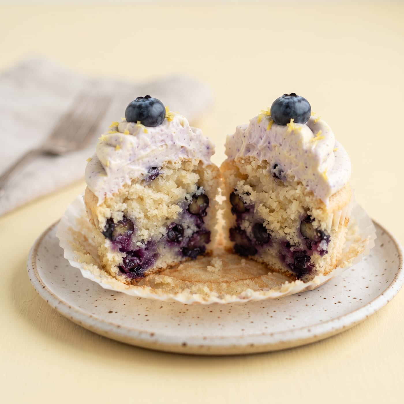 Close up cross section of a keto blueberry lemon cupcake showing berries baked into the crumb