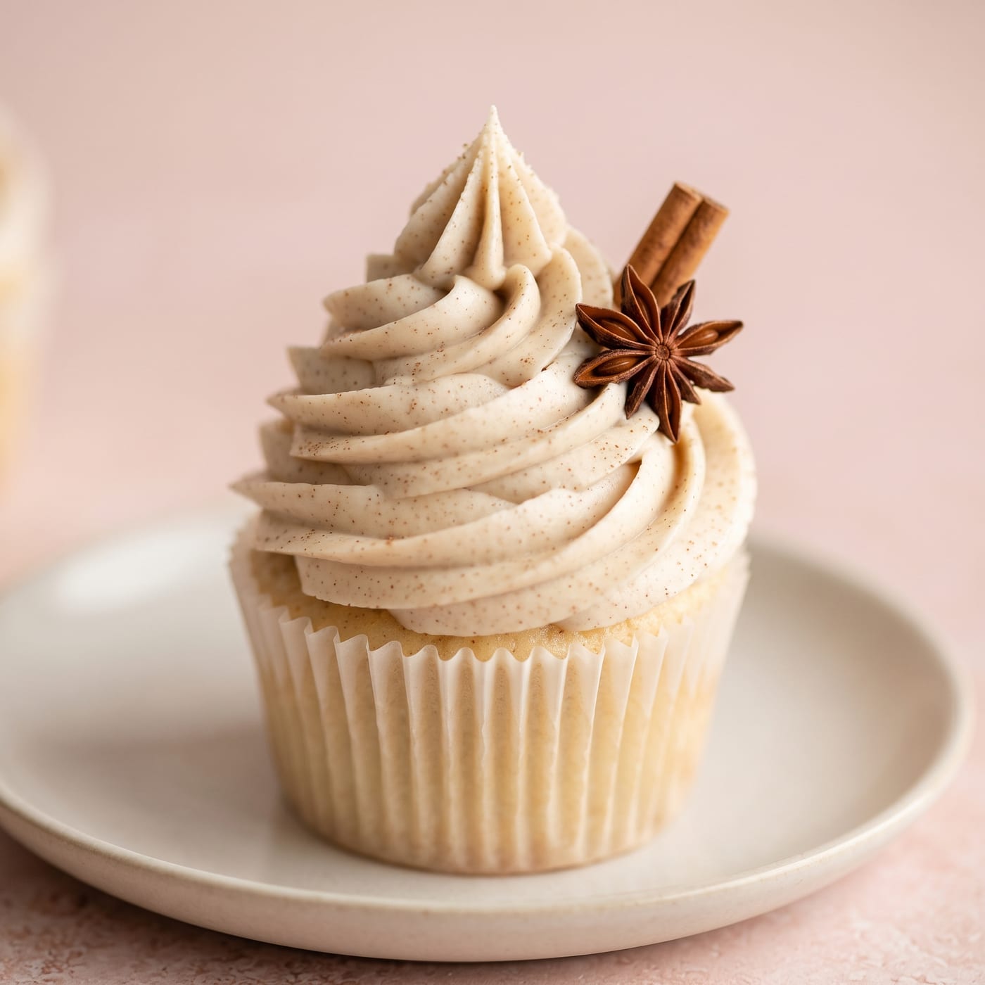 Close up of vanilla chai frosting swirl with cinnamon stick garnish on a cupcake