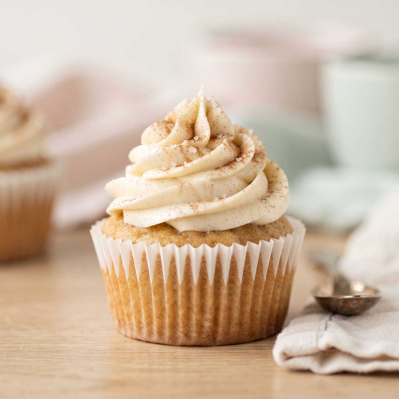 Close up of creamy vanilla frosting swirl on a keto maple cupcake with a light dusting of cinnamon
