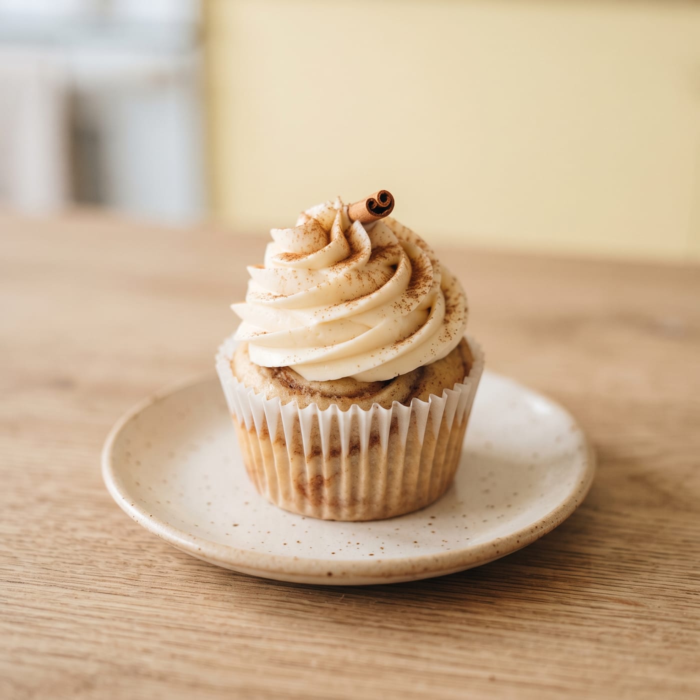 Cinnamon swirl cupcake with tall piped vanilla frosting on a pastel background
