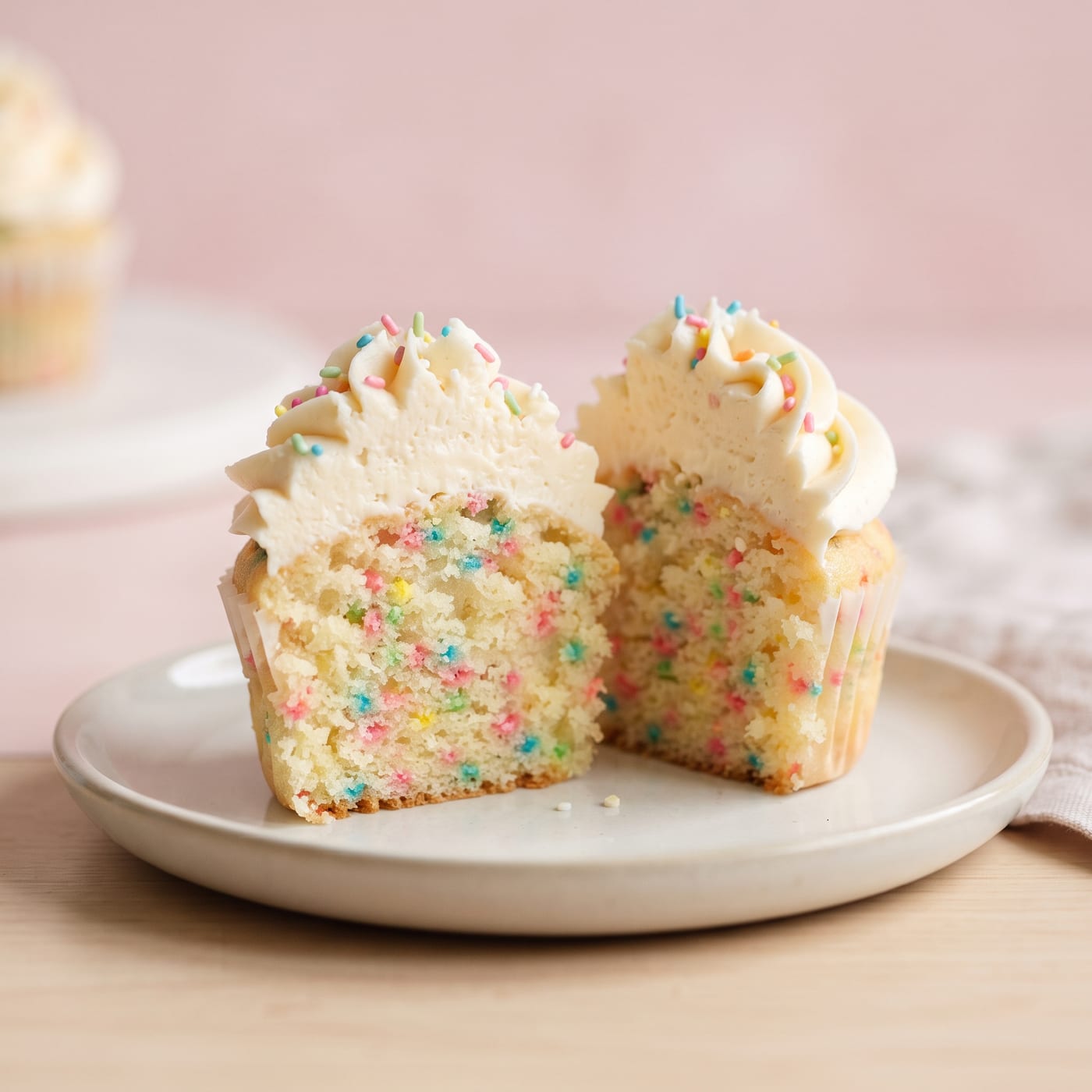 Close up of a funfetti cupcake cross section showing sprinkles baked into the soft yellow crumb