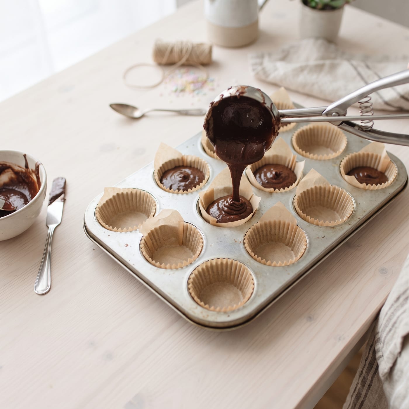 Pouring coconut milk chocolate batter into cupcake liners in a muffin pan