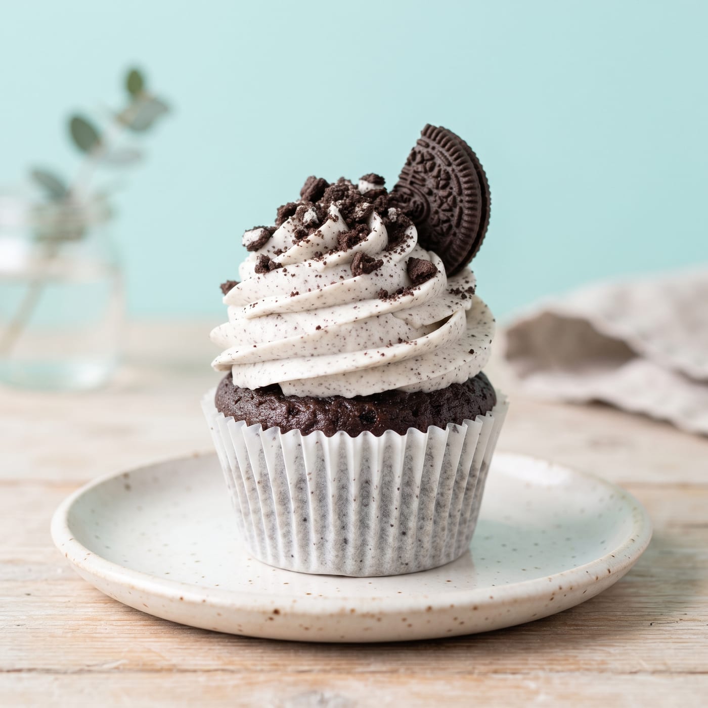 Vegan cookies and cream cupcake with tall swirled frosting and cookie crumbs on top