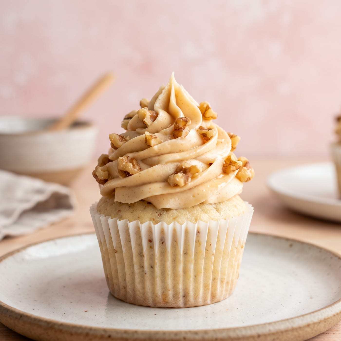 Close up of maple frosting swirl on a cupcake showing toasted walnut pieces pressed into the icing